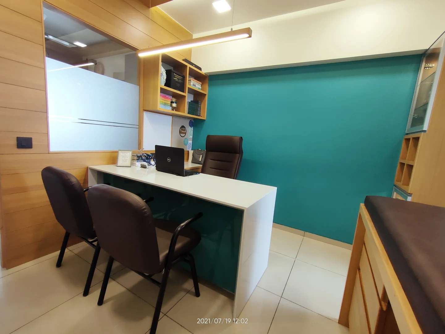 Two patient chairs at the white consulting desk, with the clinic's turquoise wall behind